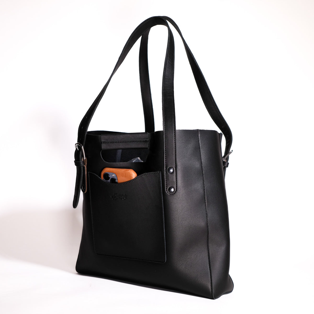 Everyday Leather Tote in Black, angled front view with shoulder handles and a phone in the front pocket