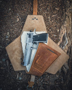 Leather Pistol Wrap in Tobacco unfolded on forest ground with a stainless pistol on the fleece lining