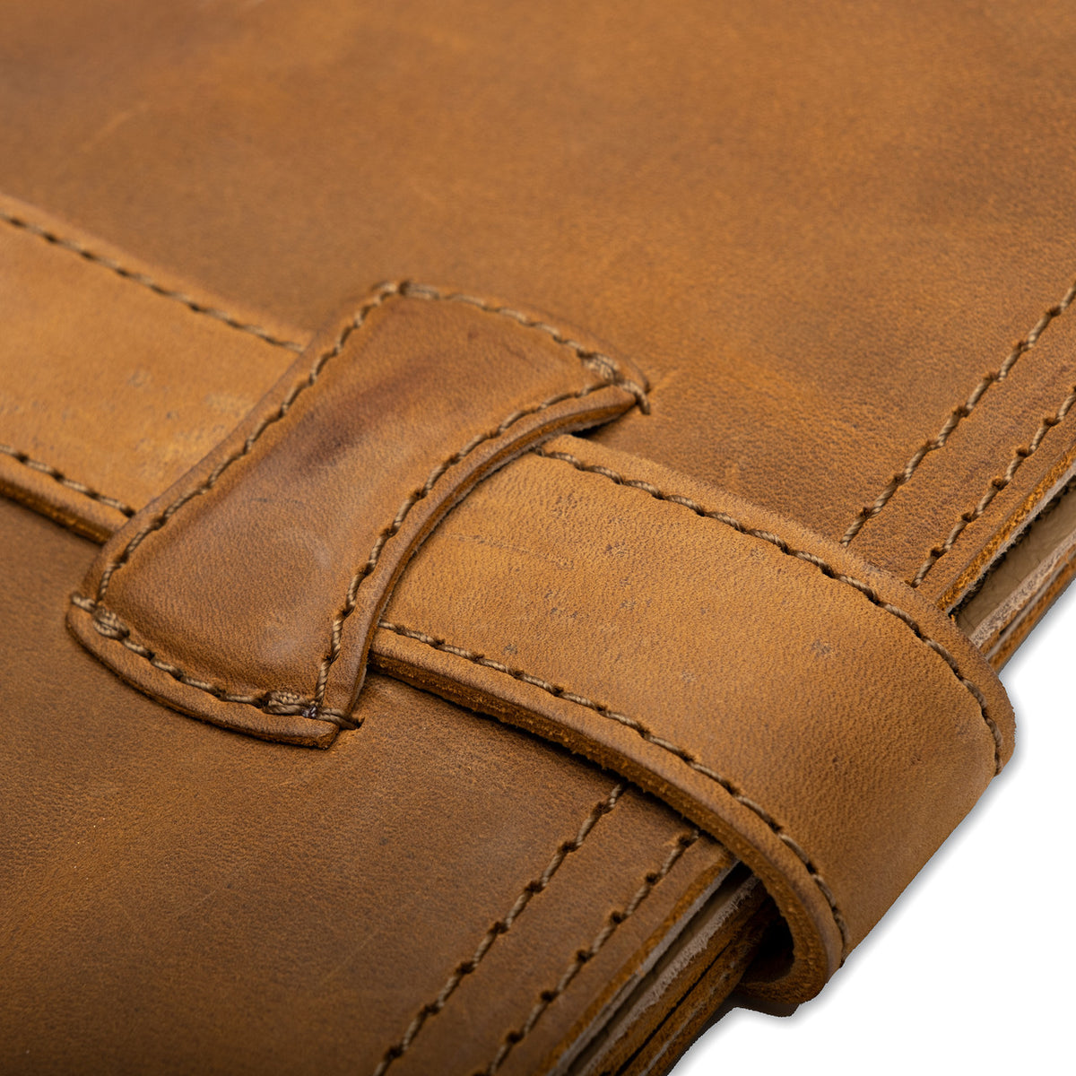 Large Leather Portfolio in Tobacco, close-up of the strap tucked through its leather loop on the front cover