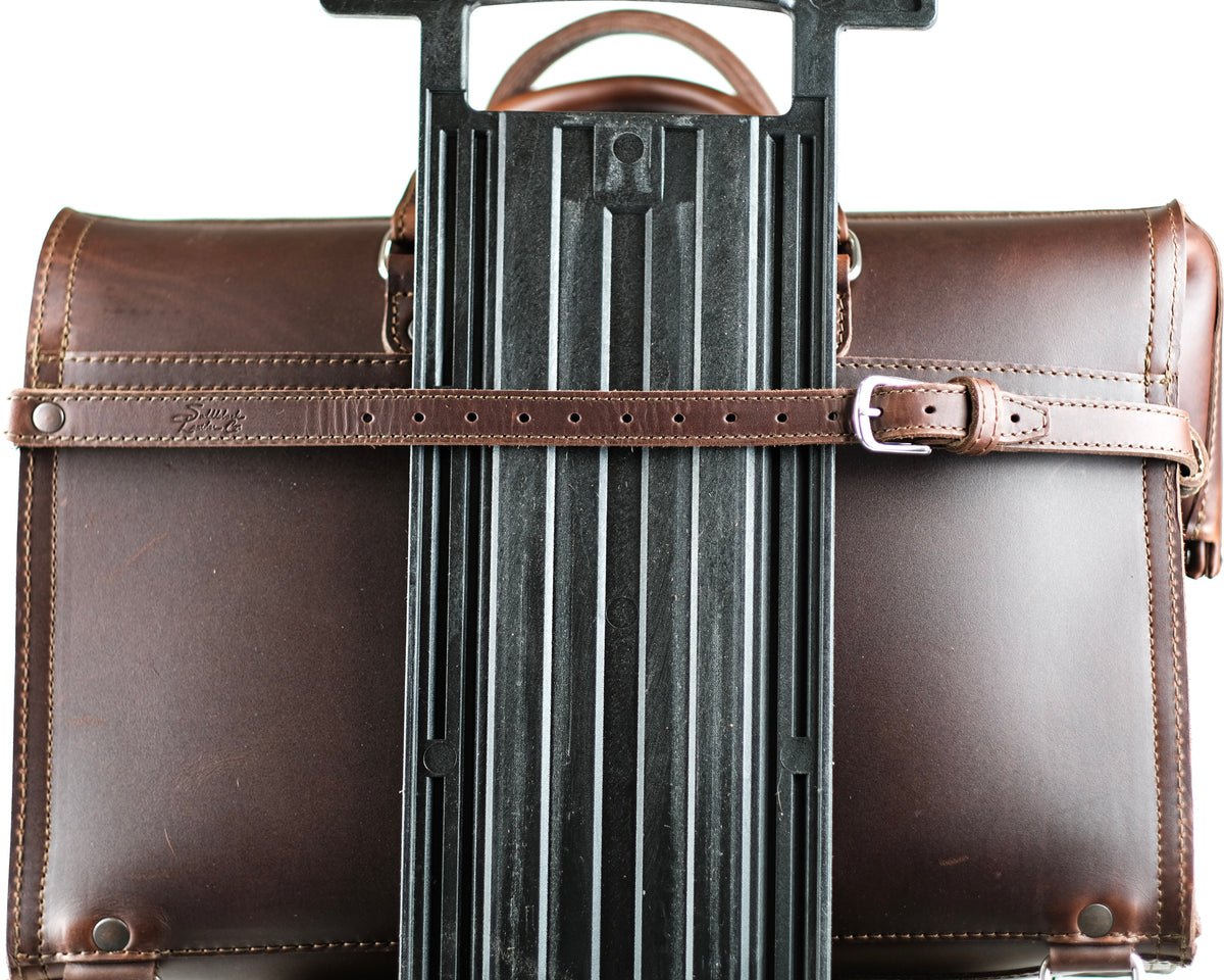 Leather Luggage Strap in Chestnut buckled around a briefcase to secure it to a rolling suitcase handle
