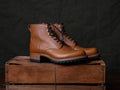 Huntsman Boots in Natural, pair with dark laces and lug soles on a wooden crate