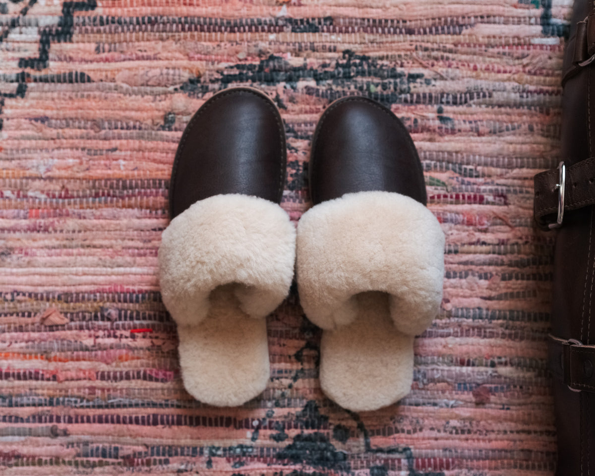 Women's Sheepskin Slippers in Dark Coffee Brown, top-down view of pair on a patterned rug