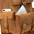 Thin Front Pocket Leather Backpack in Tobacco, close-up of front pockets holding a phone and a park map