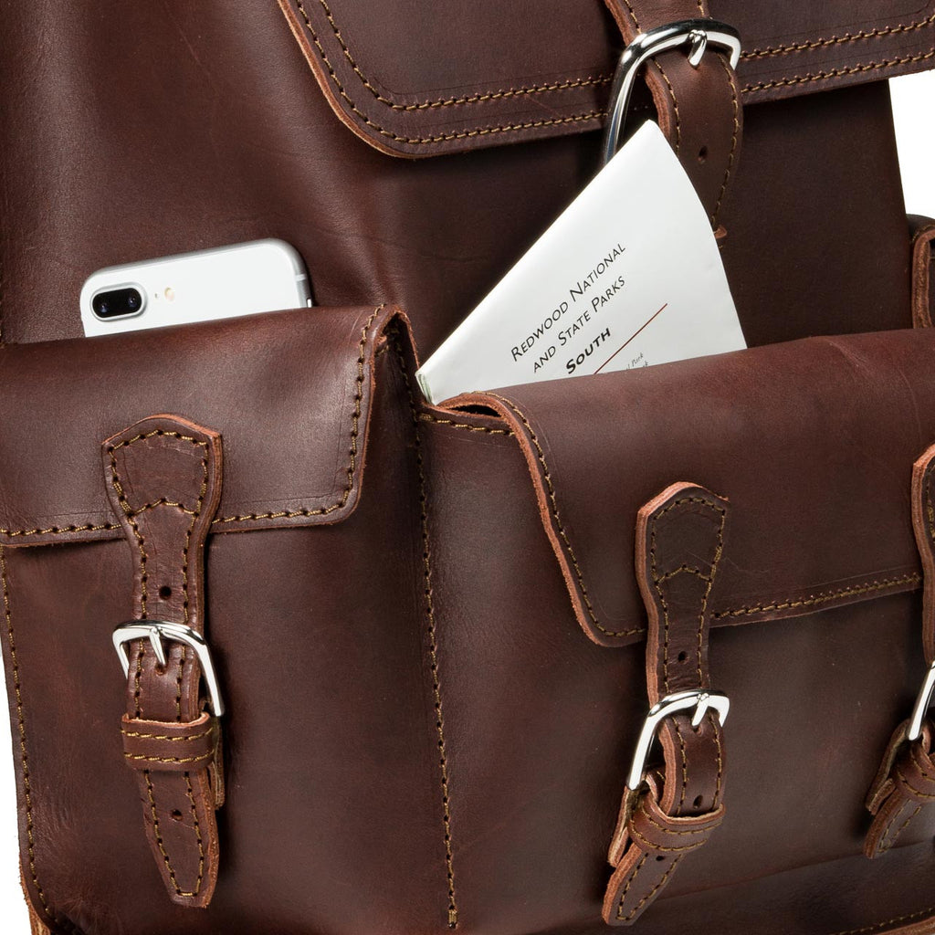 Thin Front Pocket Leather Backpack in Chestnut, close-up of front pockets holding a phone and a park map