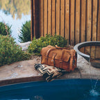 20" Baby Beast Duffle Bag in Tobacco on a patterned blanket at the edge of a poolside water feature