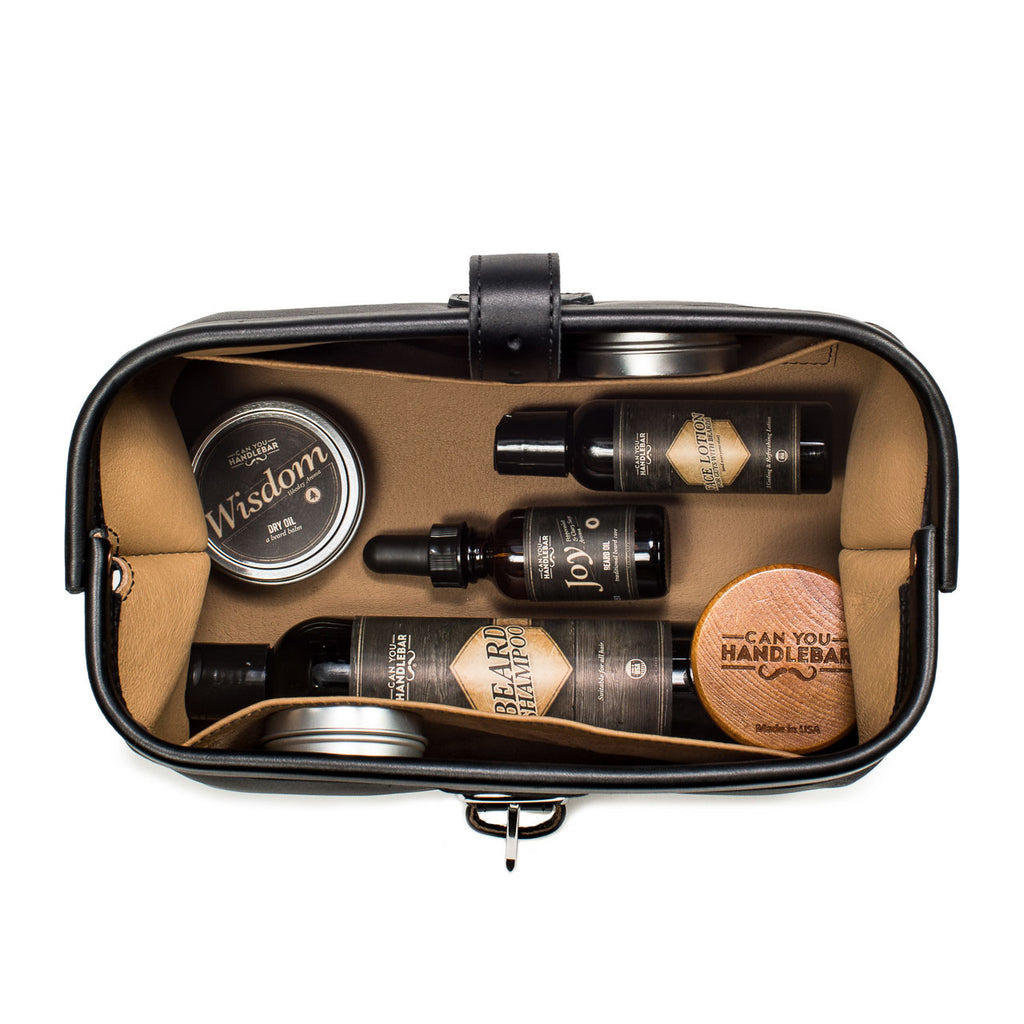Big Mouth Leather Toiletry Bag in Black, top-down view of open bag packed with beard oils and grooming tins