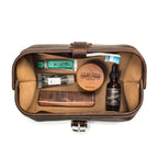 Big Mouth Leather Toiletry Bag in Dark Coffee Brown, top-down view of open bag holding toothpaste, comb and beard oil