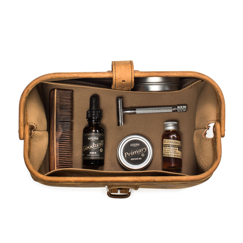 Big Mouth Leather Toiletry Bag in Tobacco, top-down view of open bag holding comb, razor and grooming products