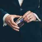 Man in a dark suit holding the Front Pocket Leather ID Wallet in Dark Coffee Brown filled with cards and cash