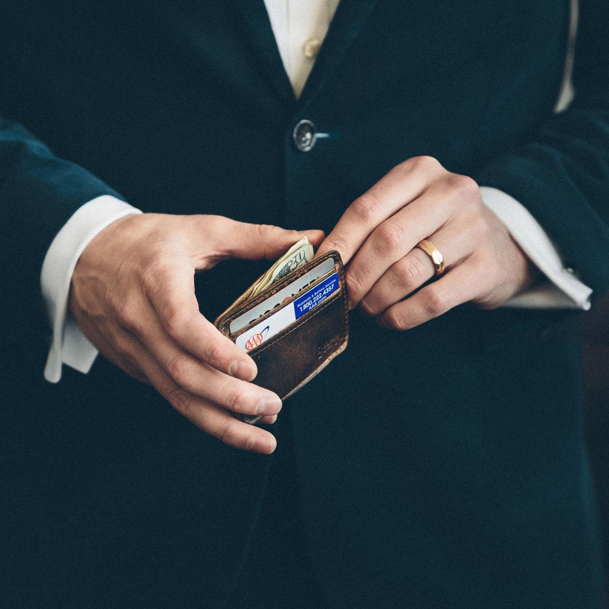 Man in a dark suit holding the Front Pocket Leather ID Wallet in Dark Coffee Brown filled with cards and cash