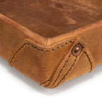 The Leather Grandfather Valet Tray in Tobacco, close-up of a stitched corner tab with copper rivet