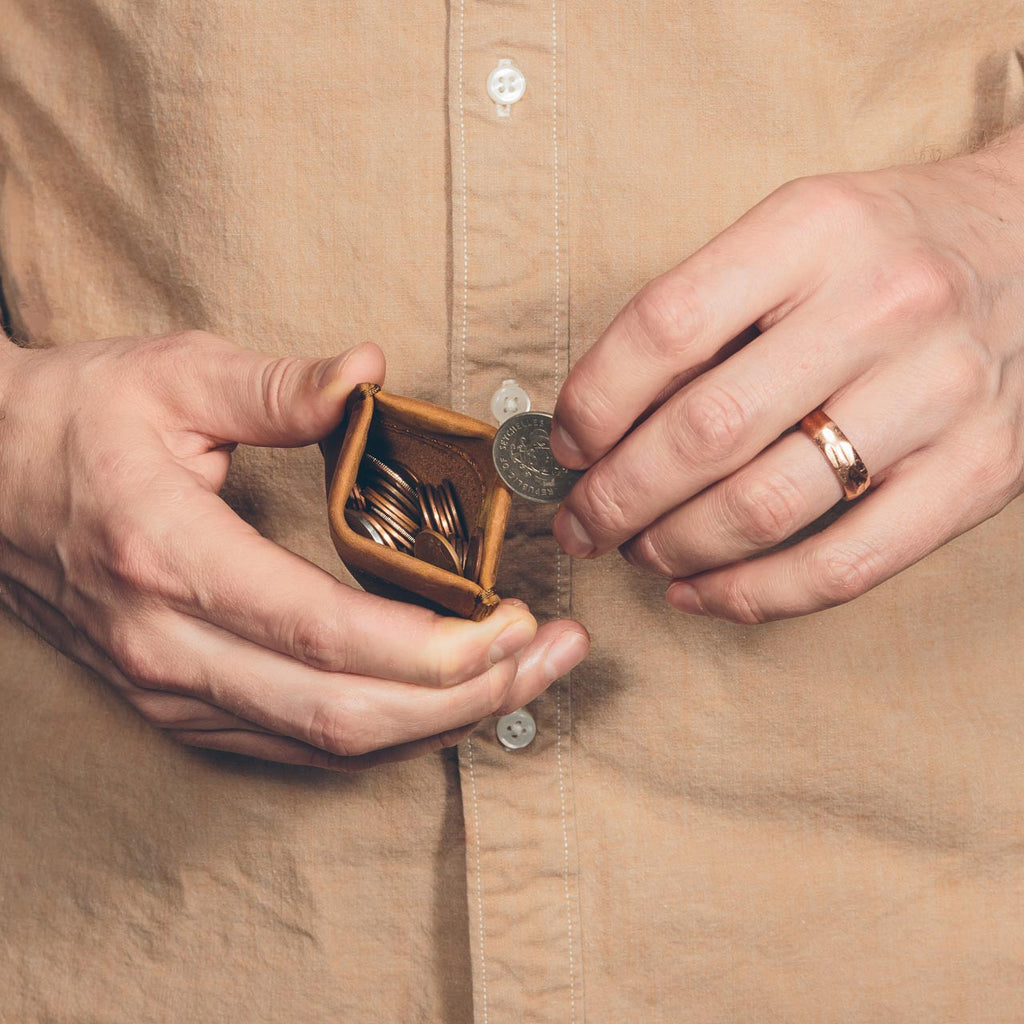 Bear Trap Leather Coin Purse in Tobacco held open by a man pulling out a coin