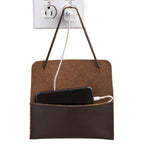 Cash & Receipt Bag in Dark Coffee Brown hung from a wall outlet by its tie, holding a charging phone