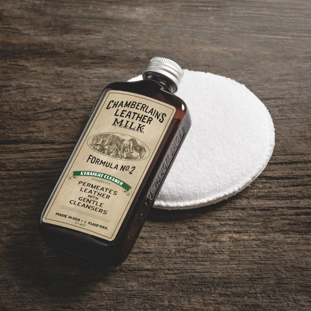 Chamberlain's No. 2 leather cleaner bottle lying on an applicator pad on a wooden table, top view