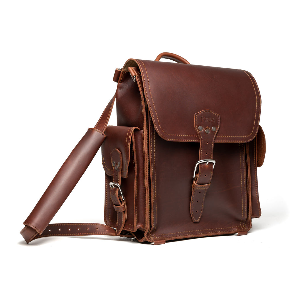 Tank Backpack in Chestnut, angled view with buckled flap, side pocket and shoulder strap