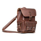 Thin Front Pocket Leather Backpack in Chestnut, angled view with buckled flap, front pocket and strap