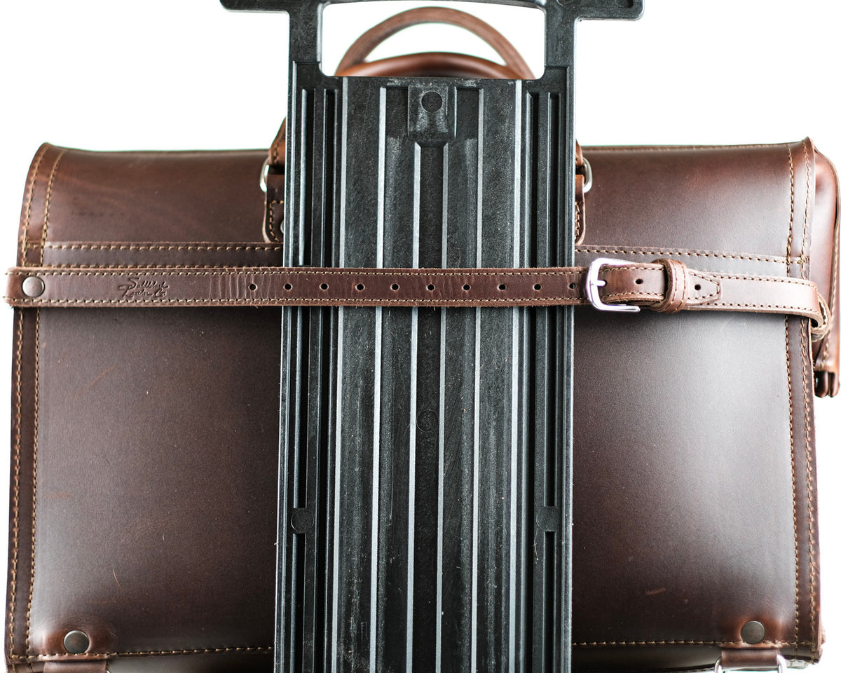 Leather Luggage Strap in Chestnut buckled around a briefcase to secure it to a rolling suitcase handle