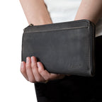Medium Wristlet Leather Wallet in black, held in hand showing front pocket and embossed logo