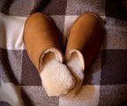 Pair of Women's Sheepskin Slippers in Tobacco on a checkered blanket, top view