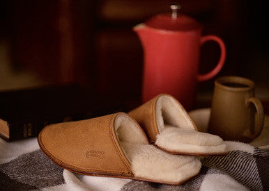 Women's Sheepskin Slippers in Tobacco on a checkered blanket beside a red teapot and mug