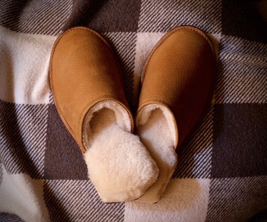 Pair of Women's Sheepskin Slippers in Tobacco on a checkered blanket, top view