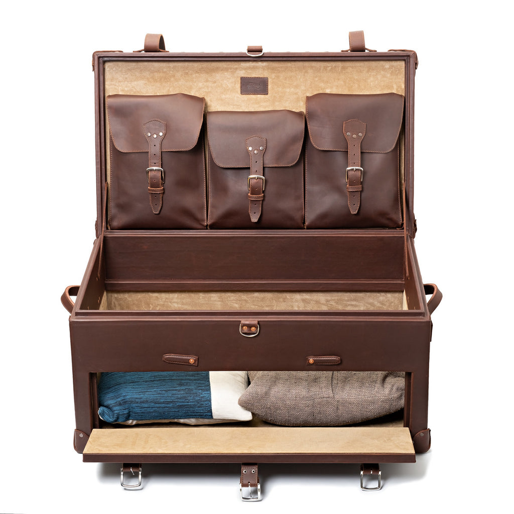 Leather Trunk in Chestnut, open with three buckled lid pockets and a drop-front drawer holding folded sweaters