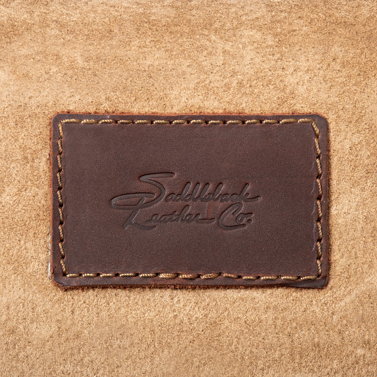 Leather Trunk, close-up of stitched leather patch with embossed Saddleback Leather Co. logo on the suede lining