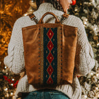 Lanita Leather Backpack in brown, worn by a woman in a knit sweater in front of holiday lights
