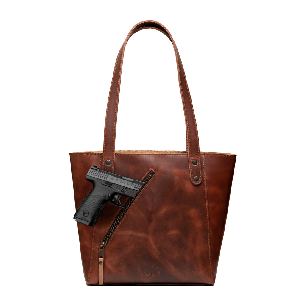 Concealed Carry Leather Tote in Chestnut, front view with a pistol emerging from the diagonal concealed carry pocket