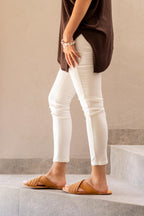 Martha Sandals in Tobacco worn with white jeans, side view standing on stone steps