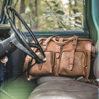 Deep Pocket Leather Duffle Bag in Tobacco sitting on the bench seat of a vintage truck behind the steering wheel
