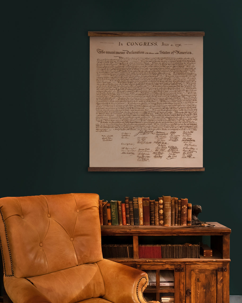 Leather Declaration Of Independence - Natural on wood rails, hung on a dark green wall above a bookcase and leather armchair