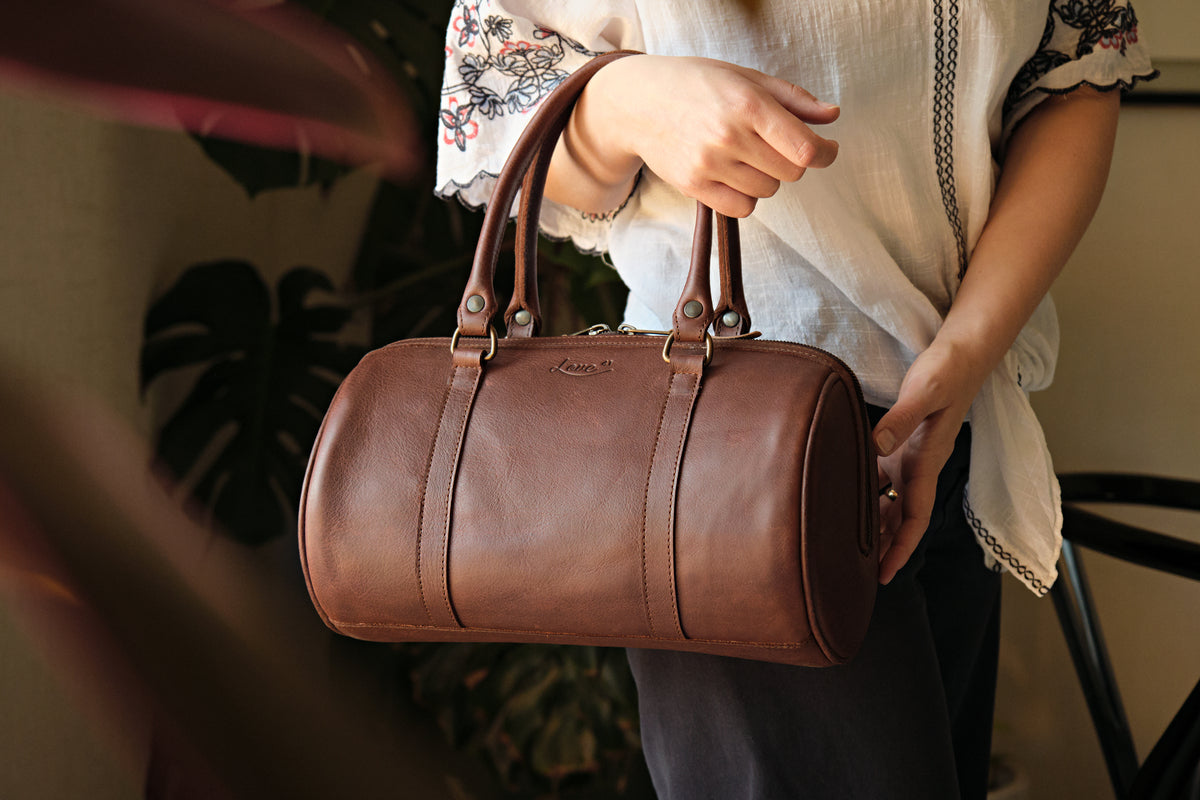 Everyday Barrel Bag in Chestnut, carried by its top handles by a woman in an embroidered blouse