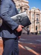 Silverback Document Holder in Black, held under the arm of a man in a suit on a city street