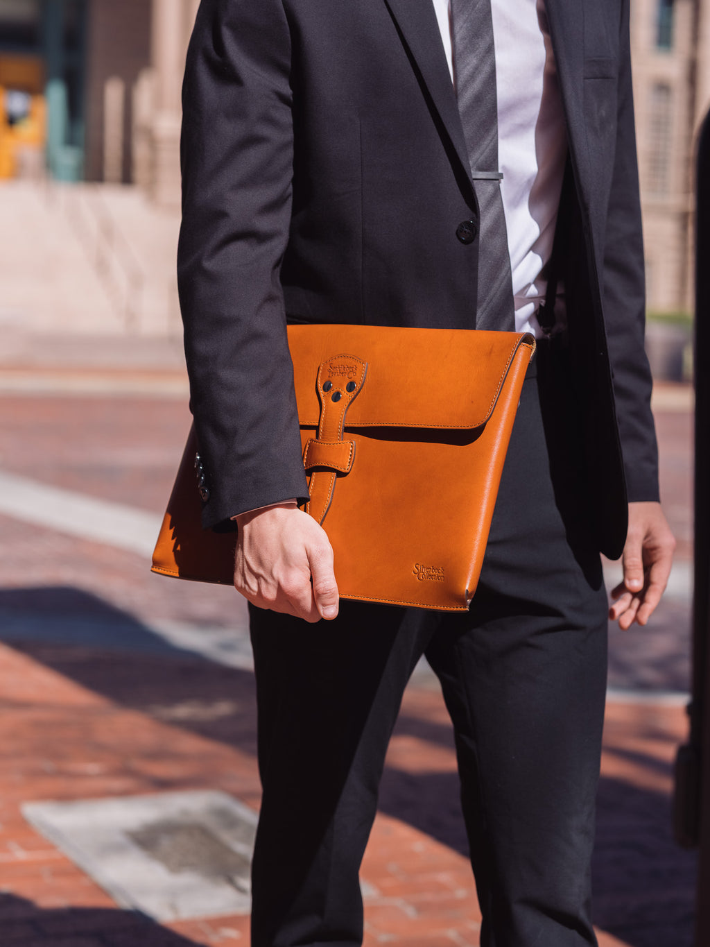 Silverback Document Holder in English Tan, held at the side of a man in a dark suit