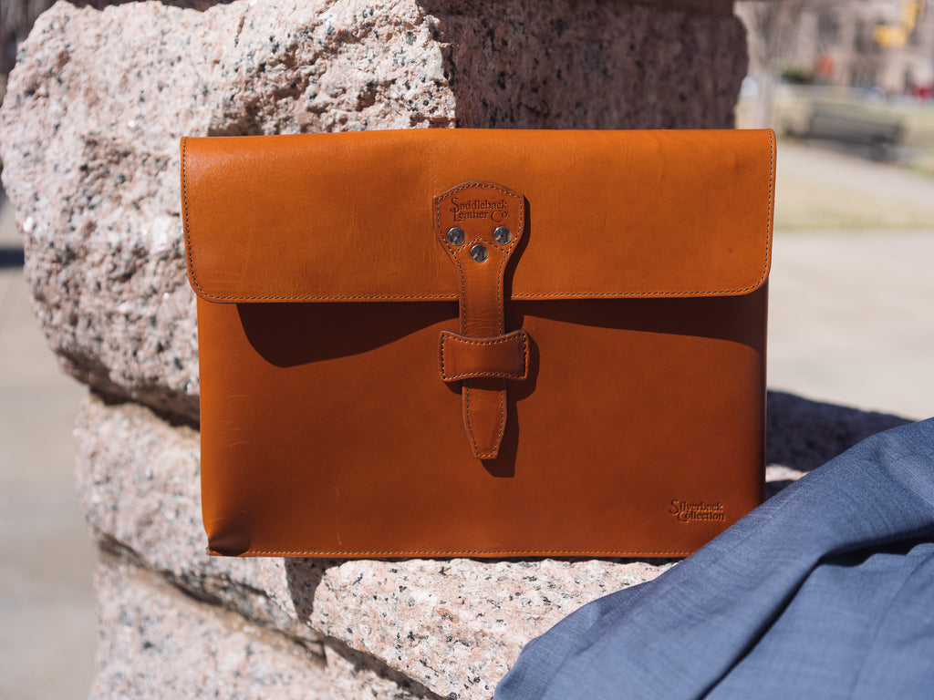 Silverback Document Holder in English Tan, propped on a granite ledge beside a blue suit jacket