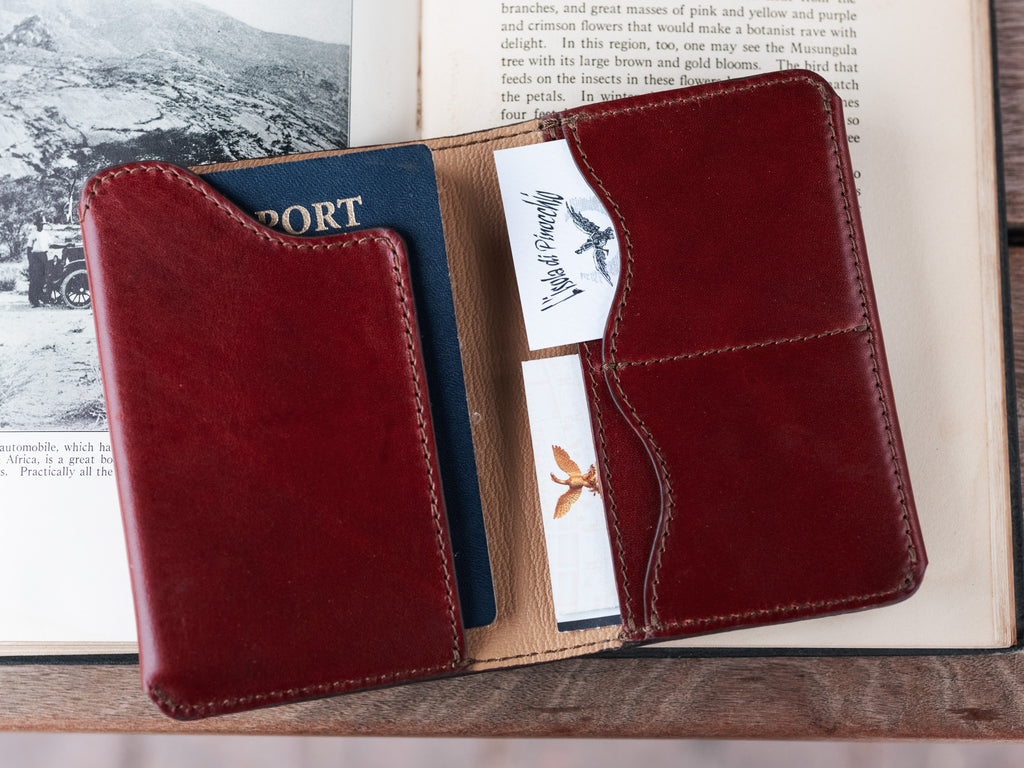 Wycliffe Passport Wallet in Oxblood, close-up open on a book showing a passport and cards in the pockets