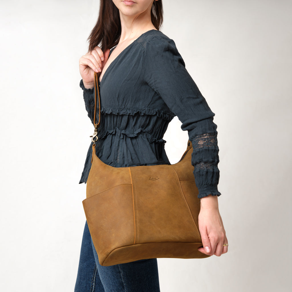 Women's Hobo Organizer Bag in Tobacco, carried on the shoulder by a woman in a dark blue blouse
