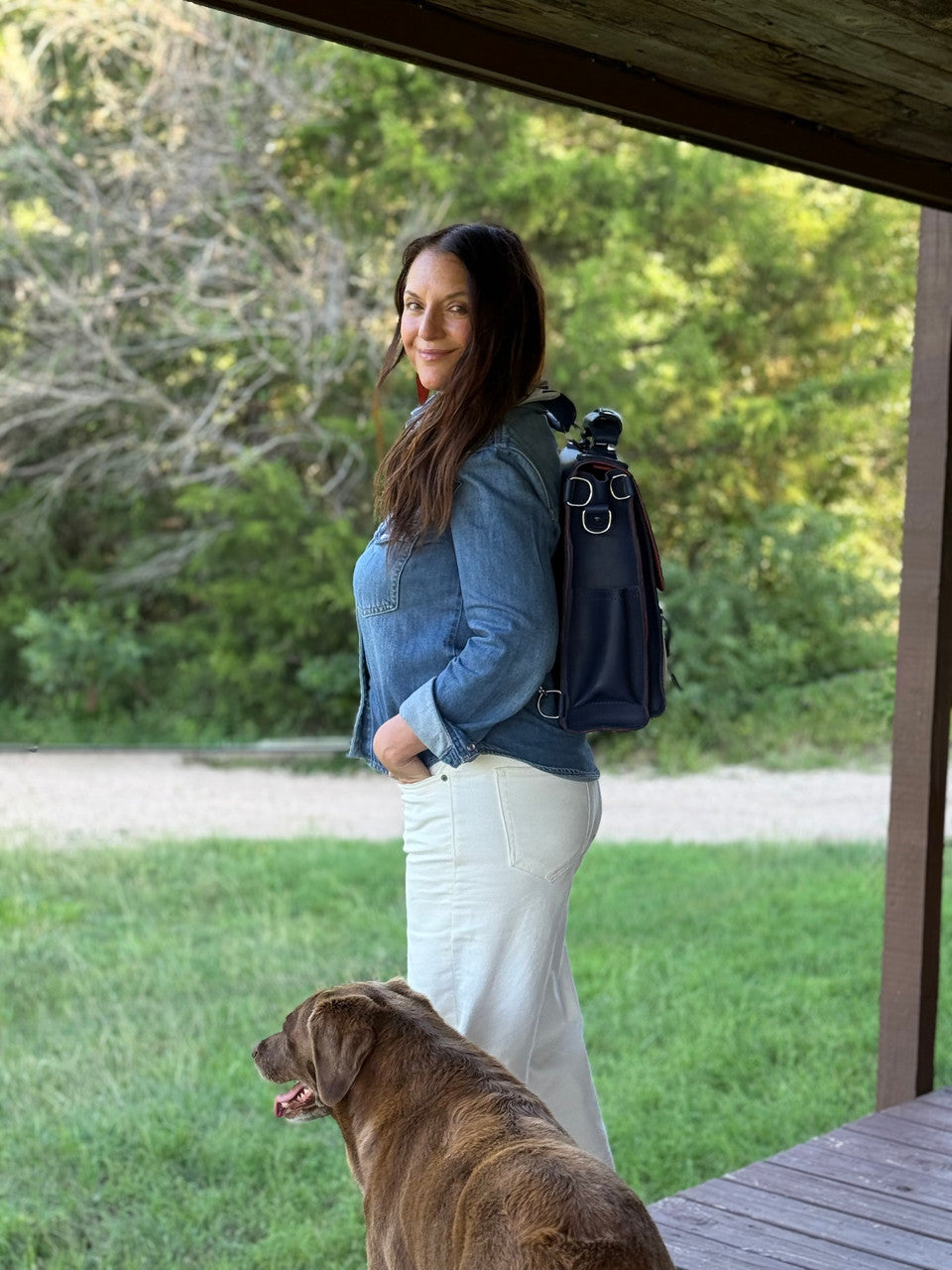 Saddleback Club Membership Paul Revere Leather Messenger Bag Backpack in Red, White and Blue, worn on a porch beside a dog