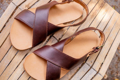 Pair of Jesus Sandals in Chestnut on a weathered wooden deck, top view