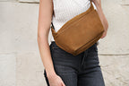 London Sling Small in Tobacco, close-up worn at the waist over dark jeans against a stone wall