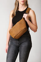 London Sling Large in Tobacco, worn across the chest by a woman in a black tank top and jeans