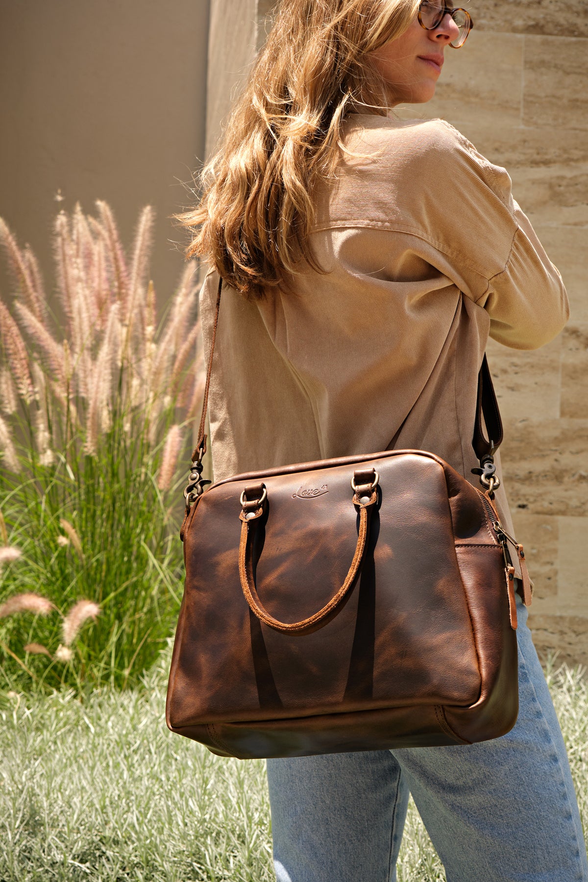 Professional Leather Satchel in Dark Coffee Brown, worn on the shoulder by a woman outdoors near tall grass