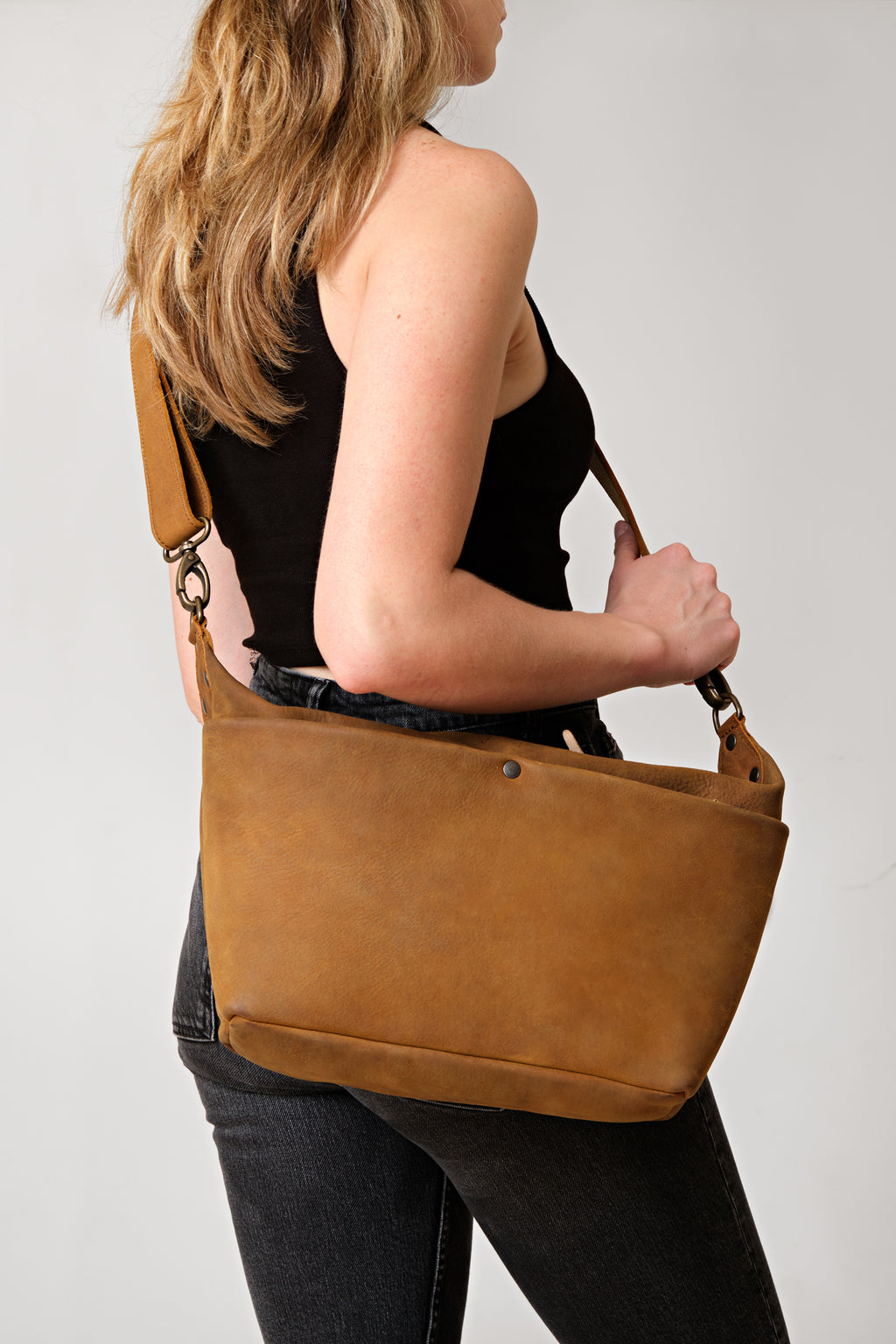 London Sling Large in Tobacco, carried on the shoulder by a woman in a black tank top