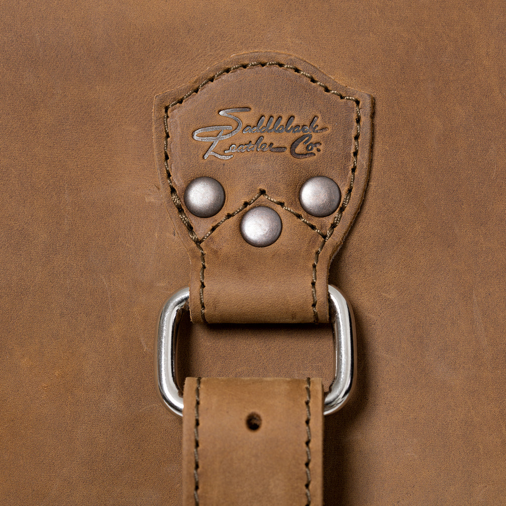 27" Adolescent Beast Duffle Bag in Tobacco, close-up of the embossed logo tab, rivets and D-ring strap