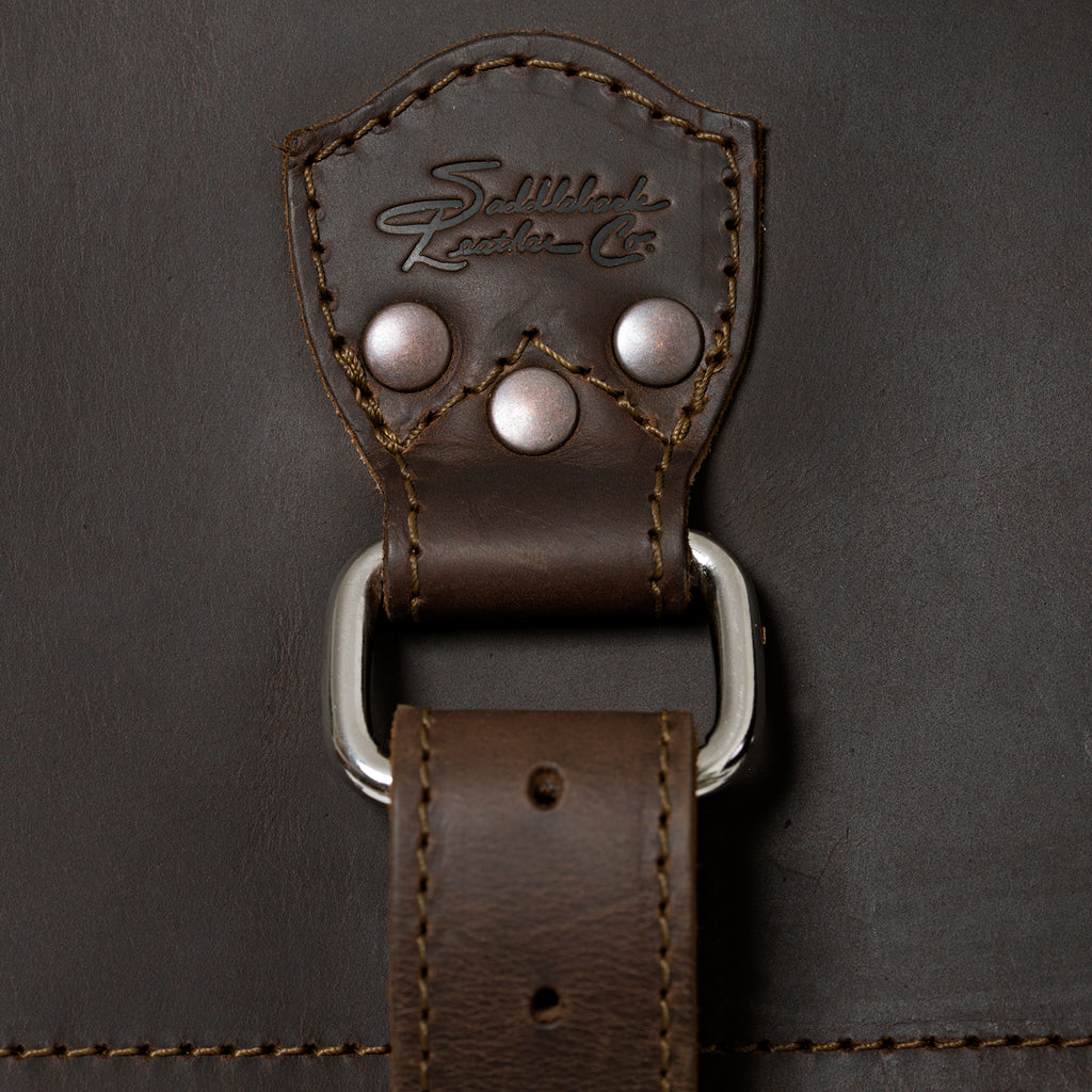 27" Adolescent Beast Duffle Bag in Dark Coffee Brown, close-up of the embossed logo tab, rivets and D-ring strap