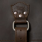 27" Adolescent Beast Duffle Bag in Dark Coffee Brown, close-up of the embossed logo tab, rivets and D-ring strap