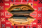Leather Organizer Satchel in Tobacco, opened wide on a red patterned rug showing a laptop, books and pouches inside
