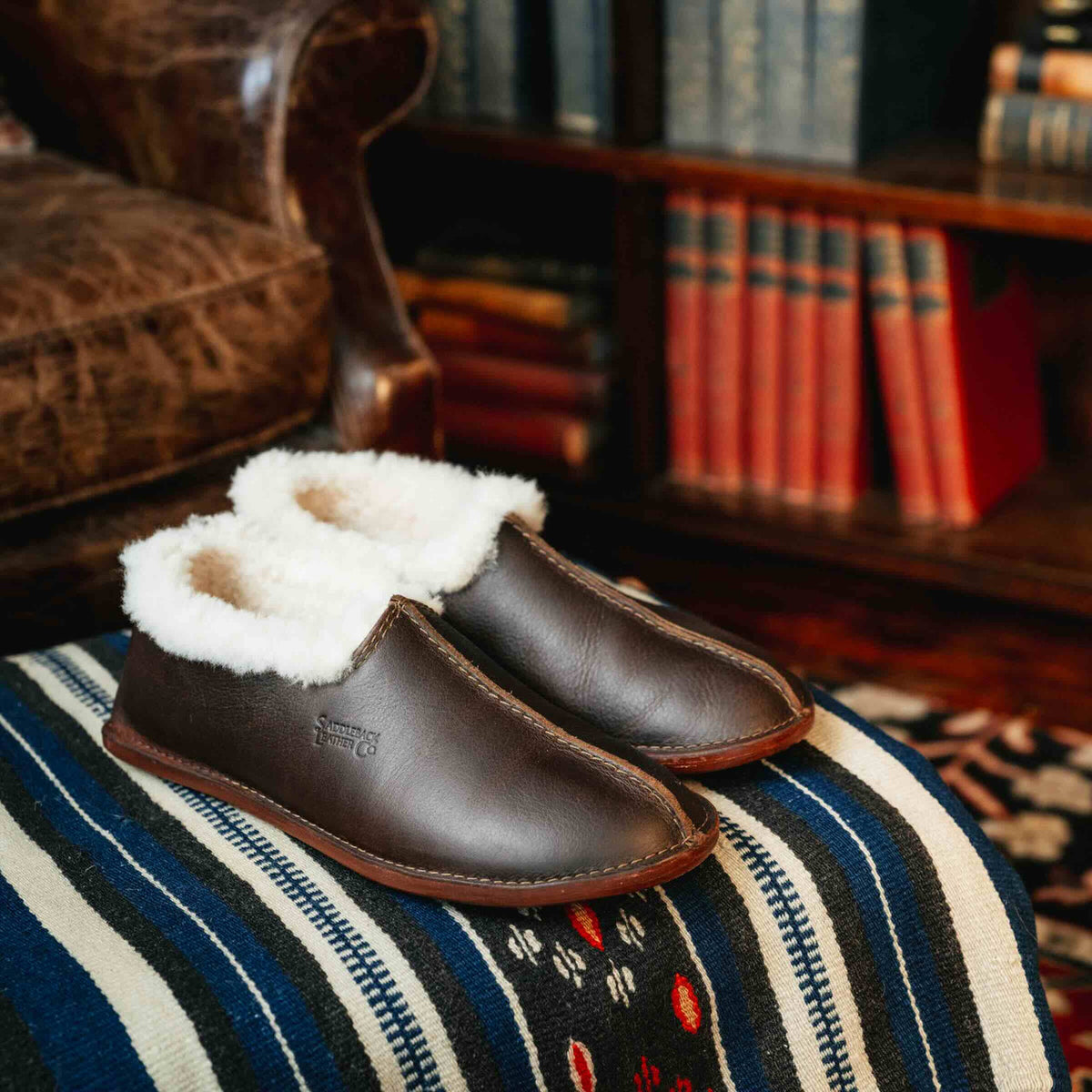 Pair of Sheepskin Moccasins in Dark Coffee Brown on a striped blanket in a library