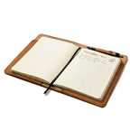 Medium Moleskin Cover in Tobacco, open at an angle with a handwritten notebook and pen in the pen loop